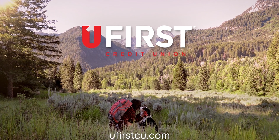 UFirst Credit Union end card: a hiker greeting her dog in a mountain meadow
